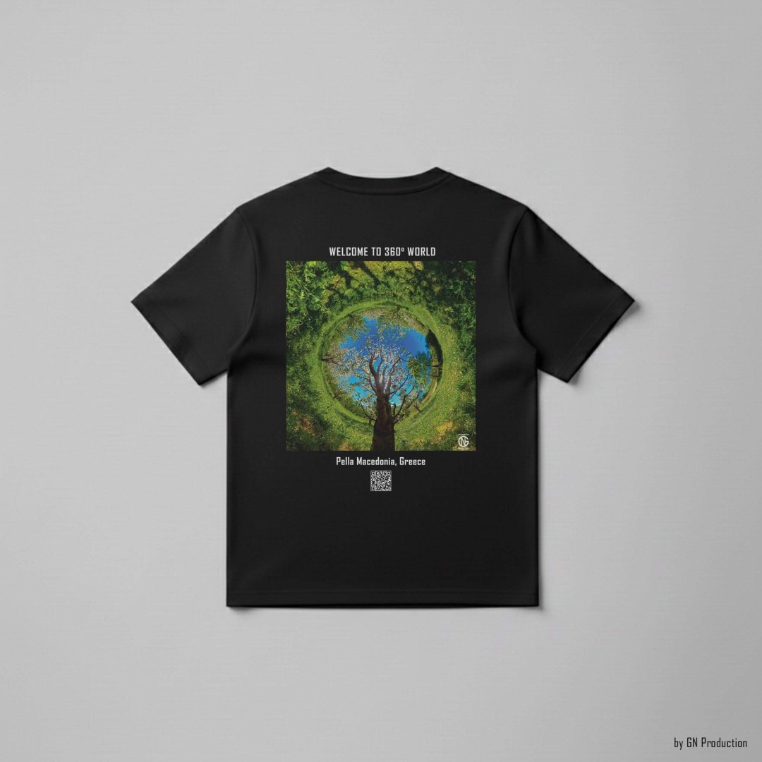 Black art T-shirt with Pella cherry orchard inverted tiny-planet 360° design, spring greenery and blossoms circling a vivid blue sky, GN Production wearable art.