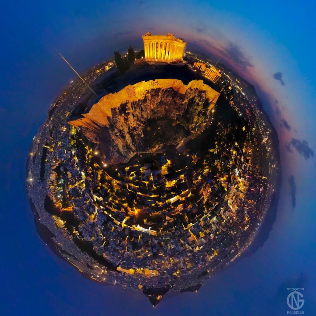 Night tiny-planet 360° view of the Acropolis: Parthenon glowing gold above Athens with deep-blue twilight sky.